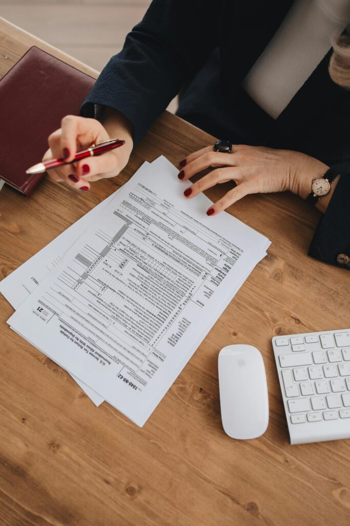 pexels photo 6927530 6927530 Top view of a business professional checking tax documents on a wooden desk.